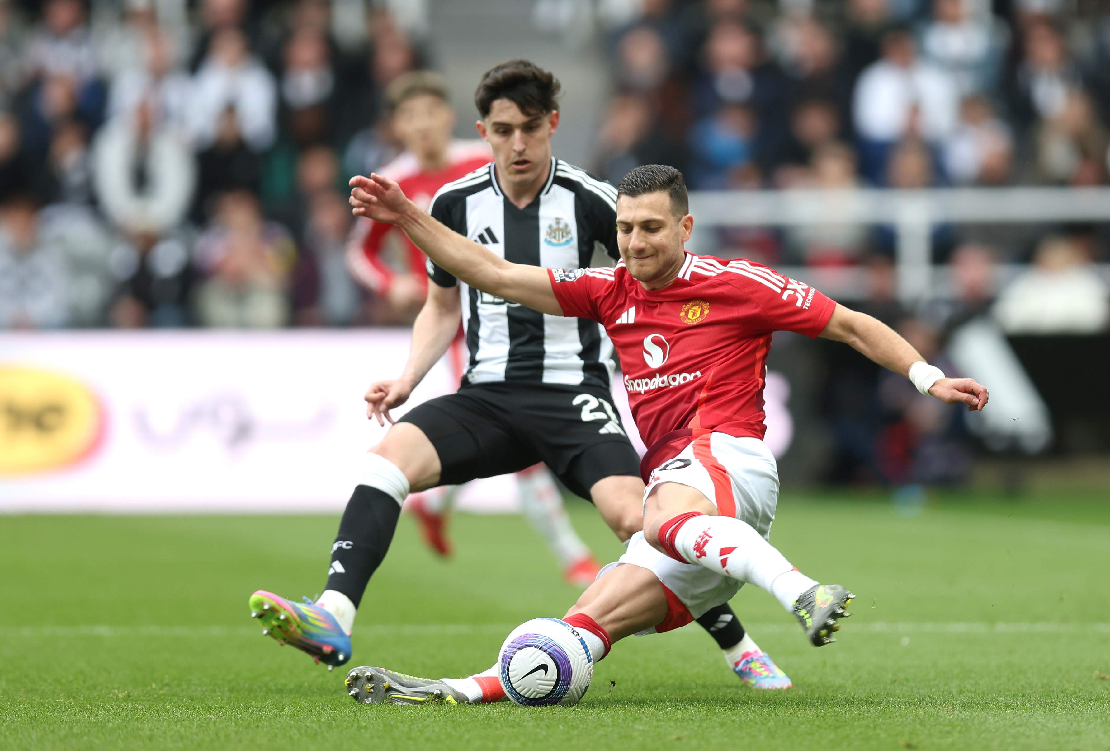 Diogo Dalot goes to ground to slide tackle the ball.