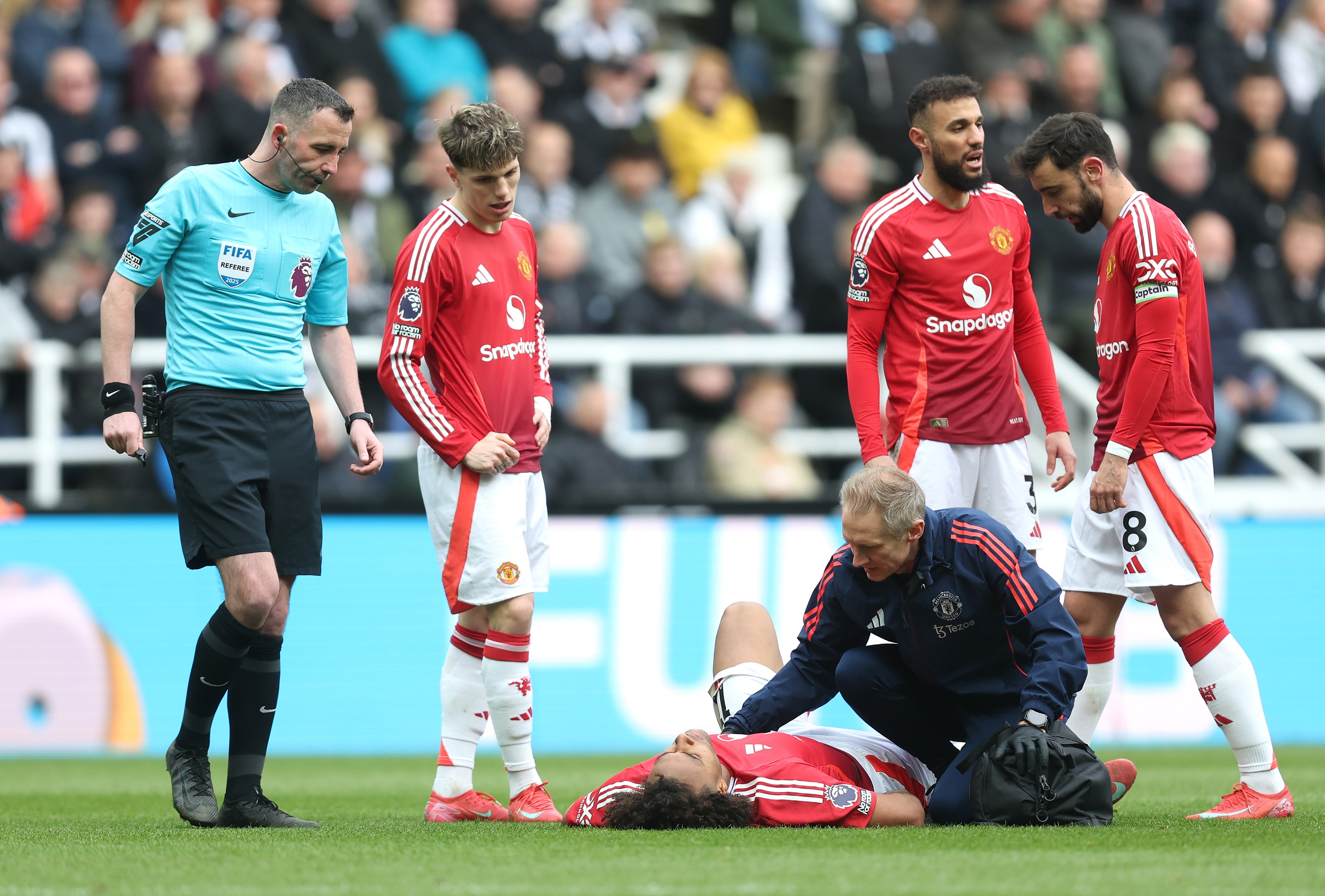 Noussair Mazraoui and Manchester United teammates stand around injured Joshua Zirkzee.