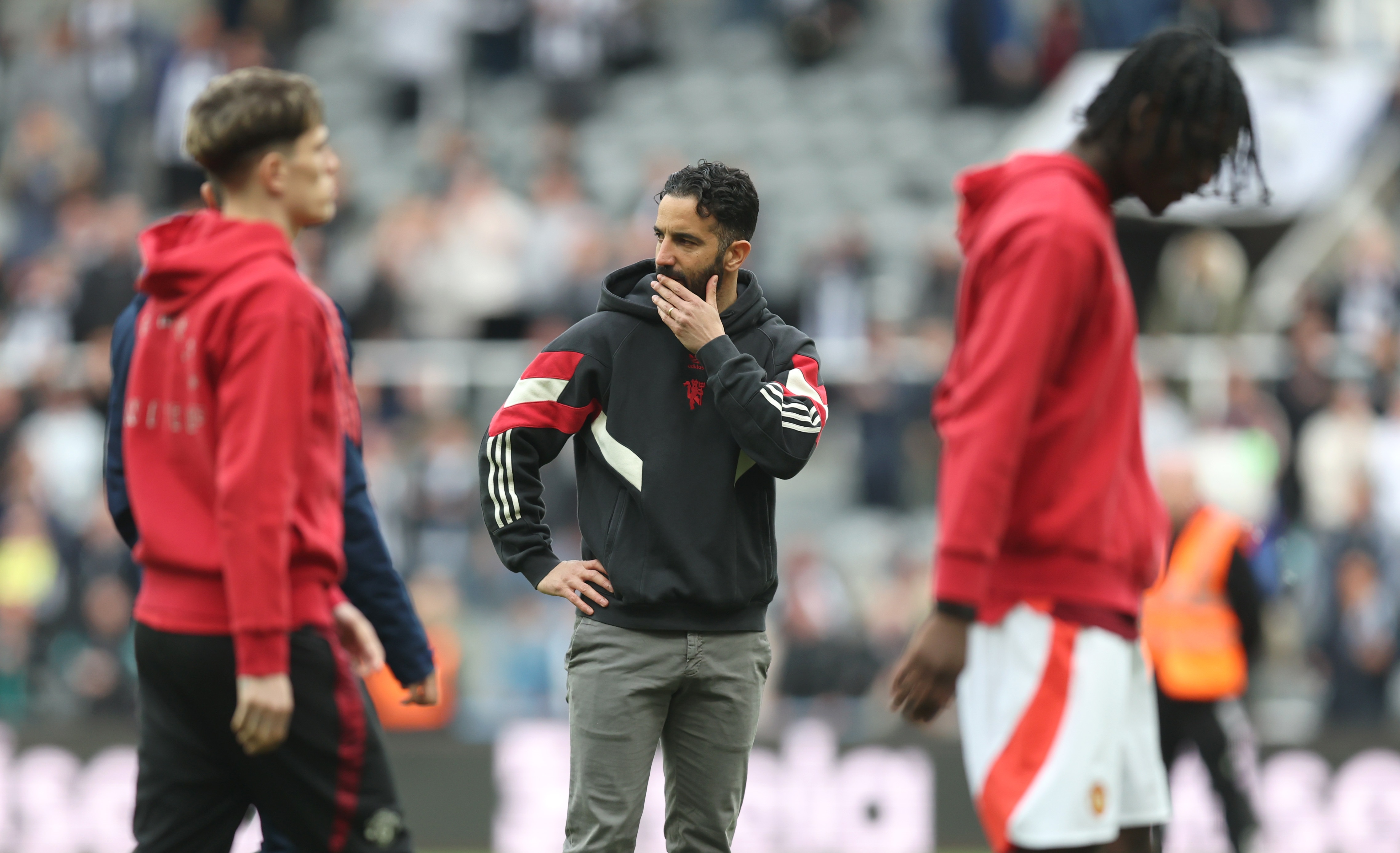 Ruben Amorim clutches his chin whilst standing between Manchester United players.