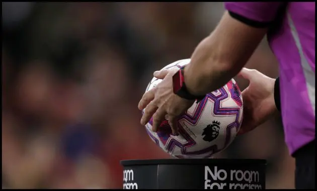 Premier League referee picks up the ball from the stand ahead of kick-off.