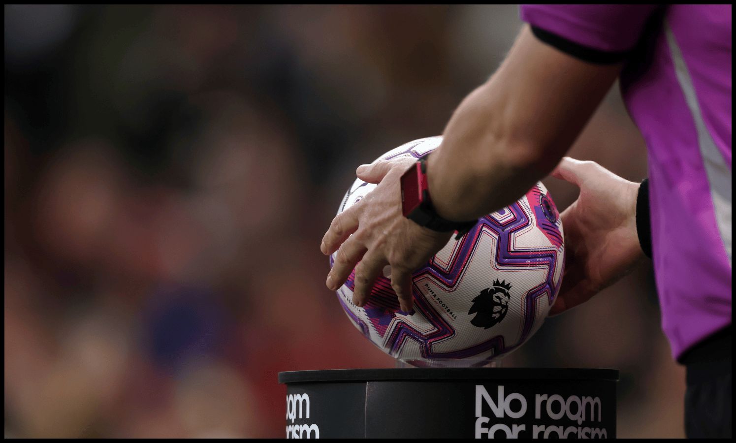 Premier League referee picks up the ball from the stand ahead of kick-off.
