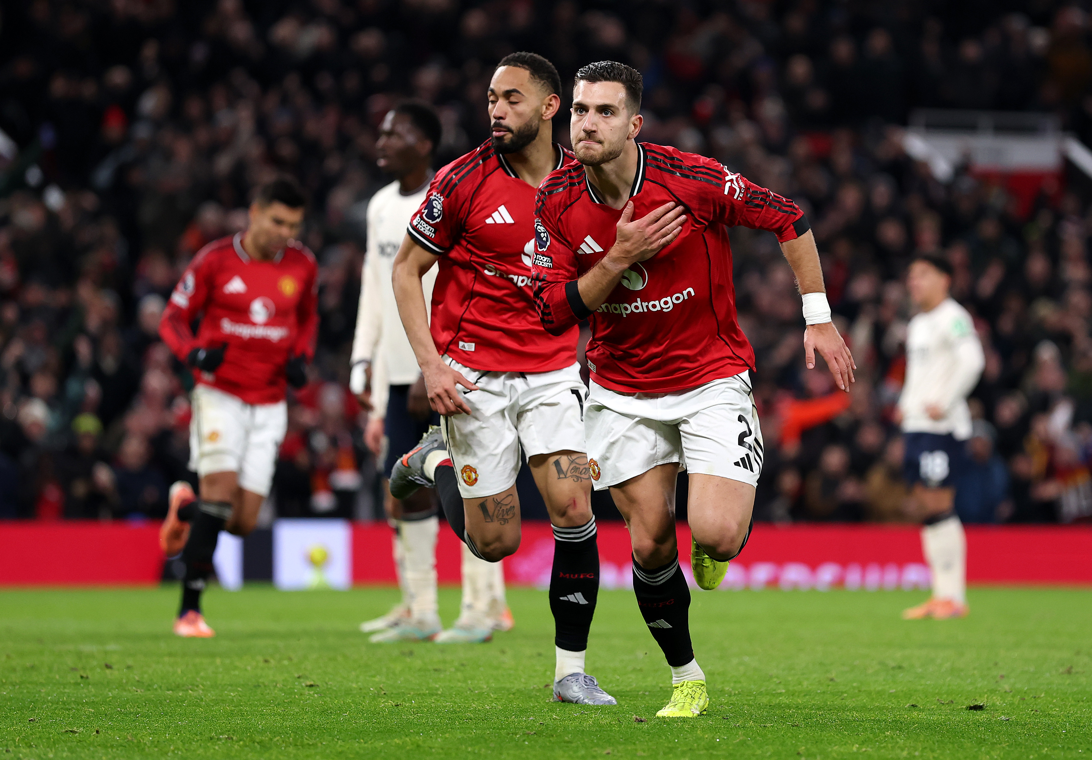 Diogo Dalot celebrates by patting the Man United badge after scoring against West Ham.