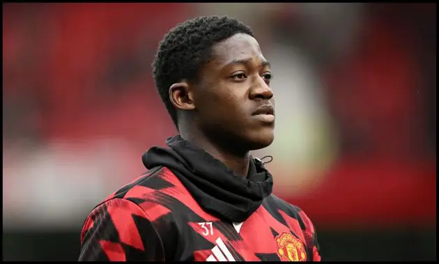 Kobbie Mainoo looks on while warming up for Man United.