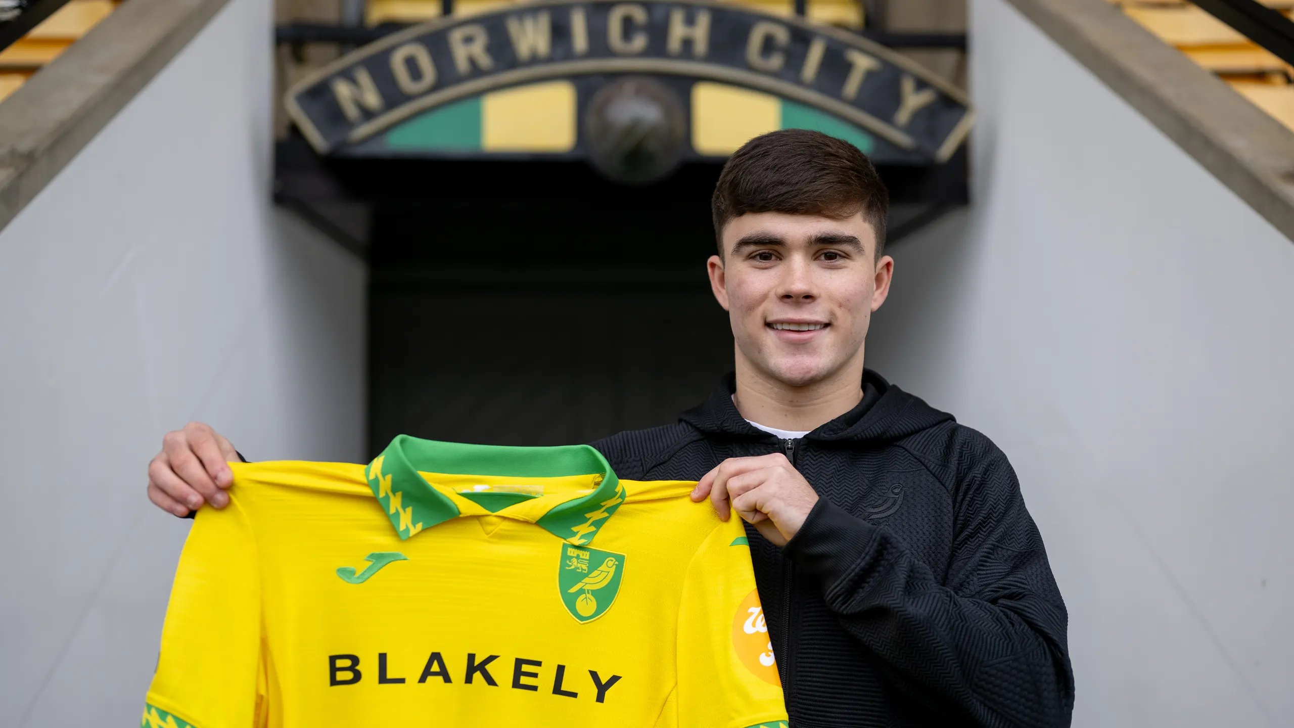 Harry Amass holds a Norwich shirt after joining the club on loan.