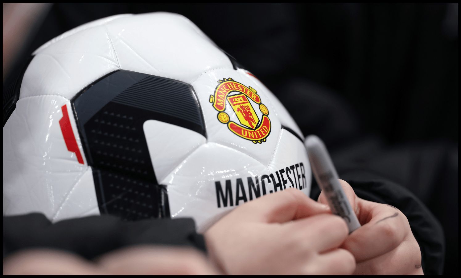 A Man United fan holds club ball outside Old Trafford.