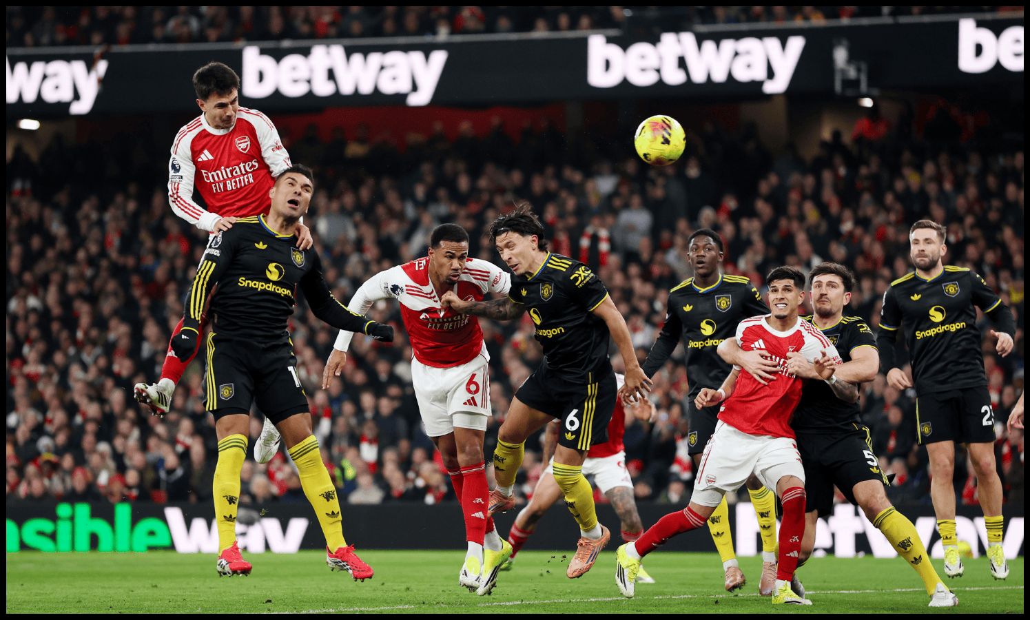 Man United and Arsenal players jump for a corner.