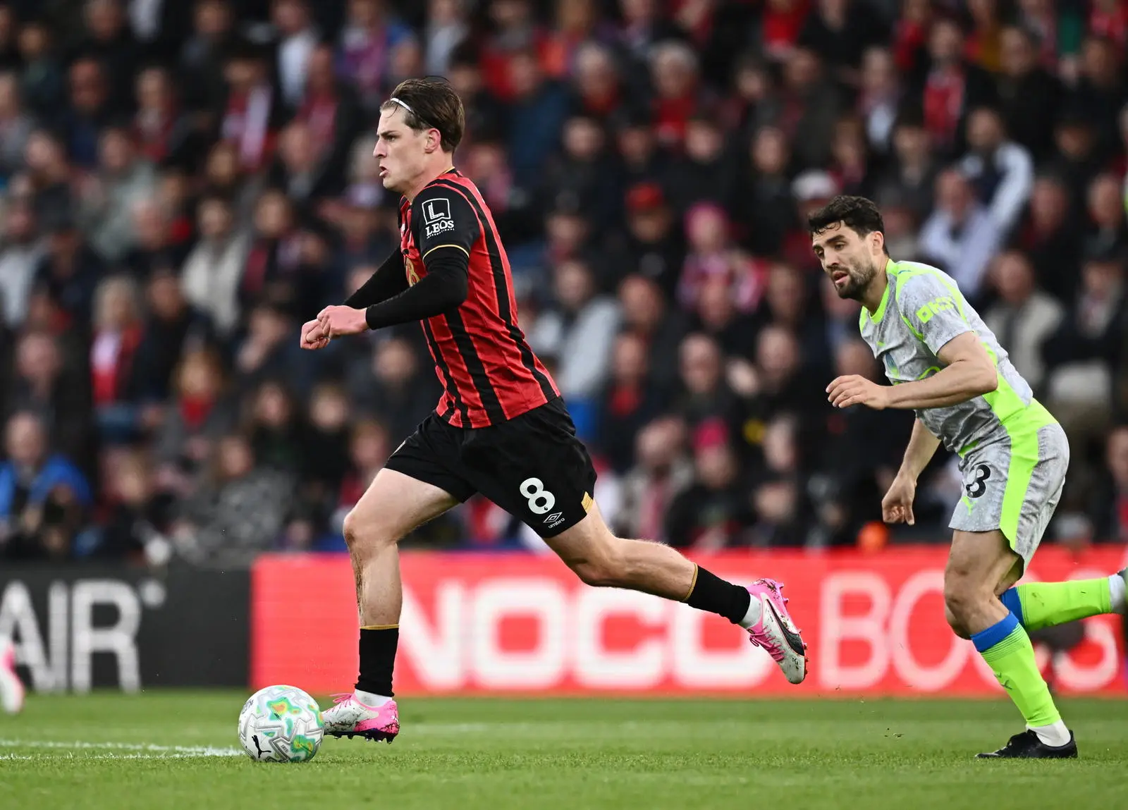 Bournemouth midfielder sprinting with the ball during a soccer match.