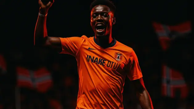 Ivory Coast footballer celebrates World Cup goal against Norway in orange kit under stadium lights