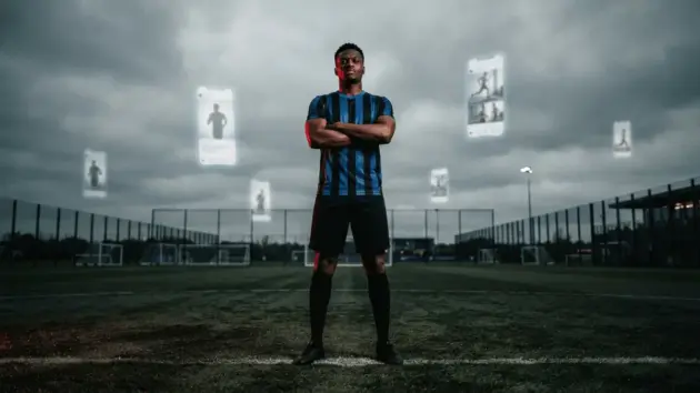 Footballer in striped jersey standing confidently on training ground after failed transfer