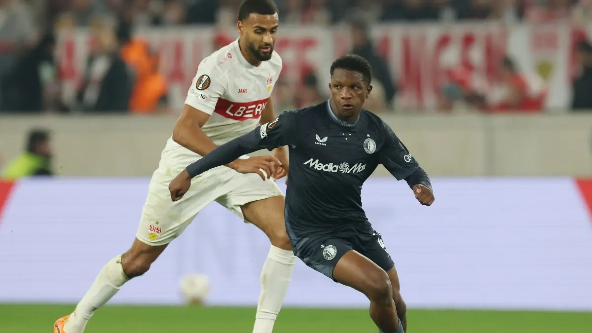 Givairo Reid of Feyenoord in a dark blue kit dribbling the ball past an opponent in a white kit.