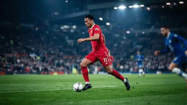 Manchester United striker performing skillful dribble during pre-season match under stadium lights