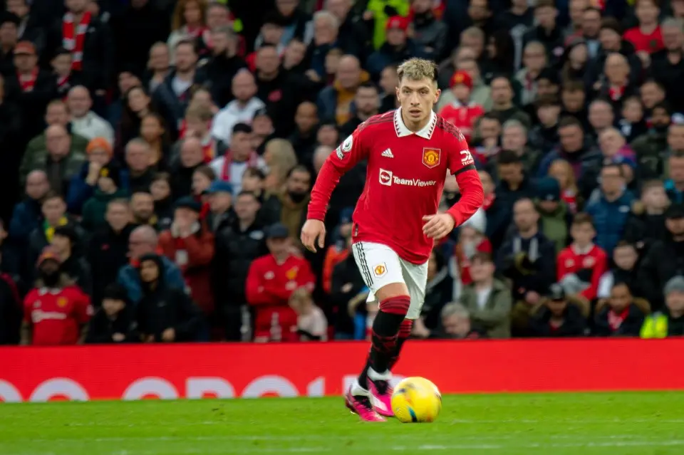 Lisandro Martinez in a red Manchester United kit running with a football during a match