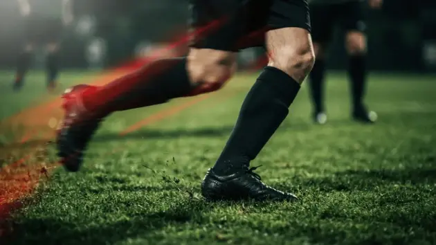 Football midfielder in motion on pitch with dramatic red and black lighting