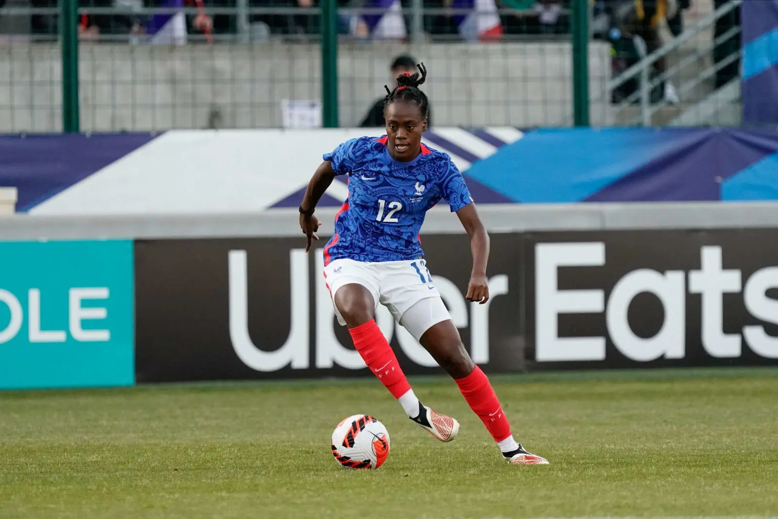Soccer player in blue France jersey dribbling ball on field.