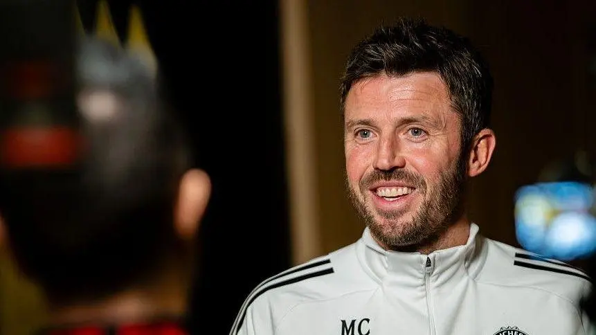 Michael Carrick speaking during an interview wearing a Manchester United tracksuit.