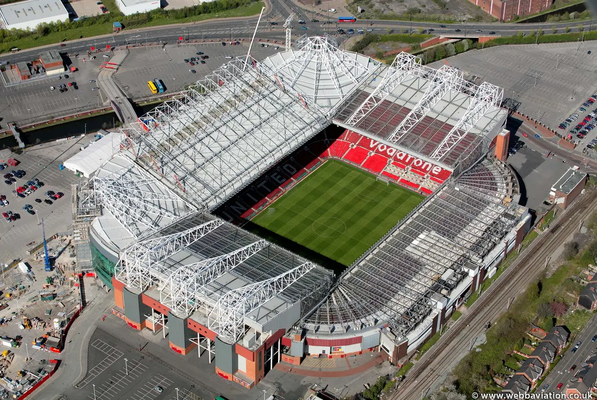 Aerial view of Old Trafford stadium in Manchester, showcasing its structure and green pitch.