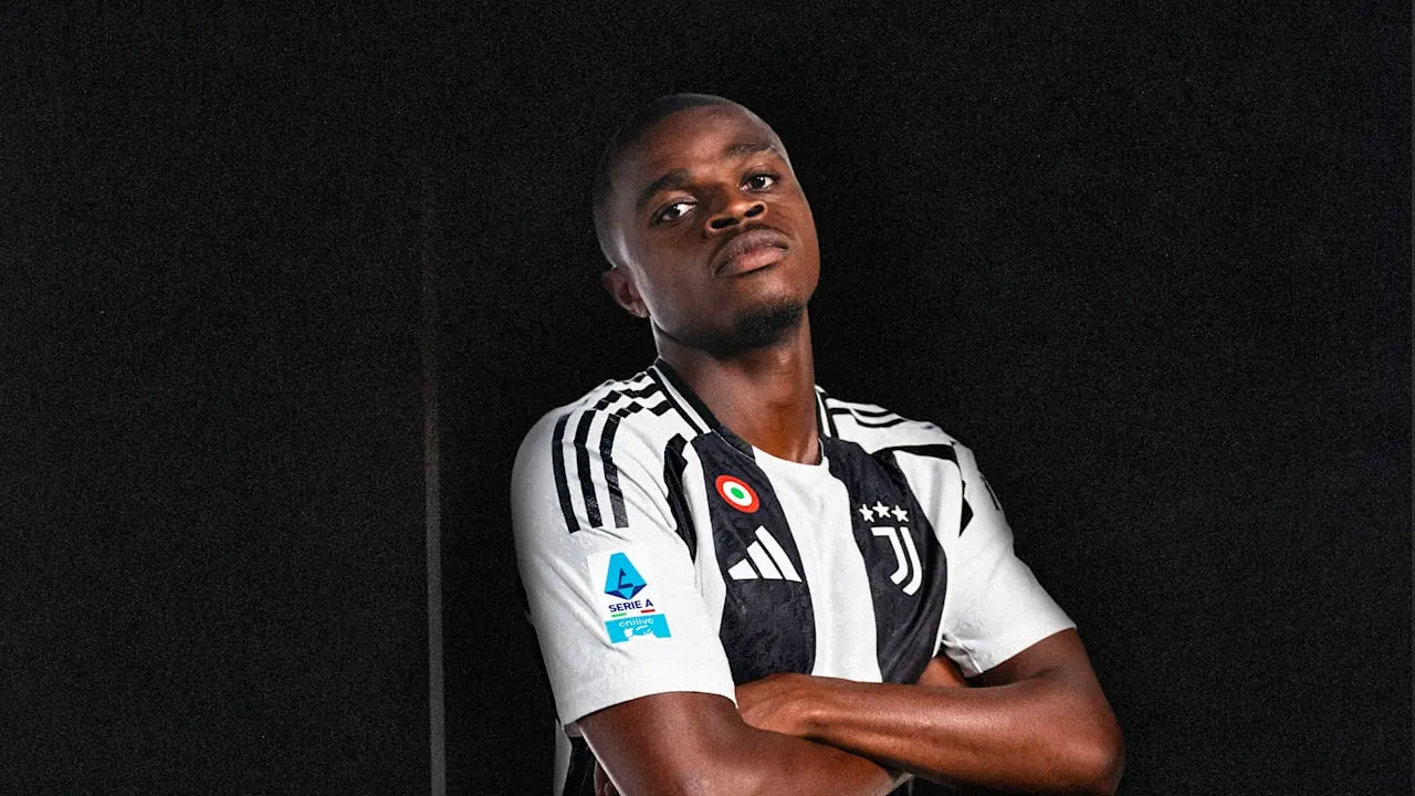 Pierre Kalulu in Juventus jersey striking a pose against a dark background.
