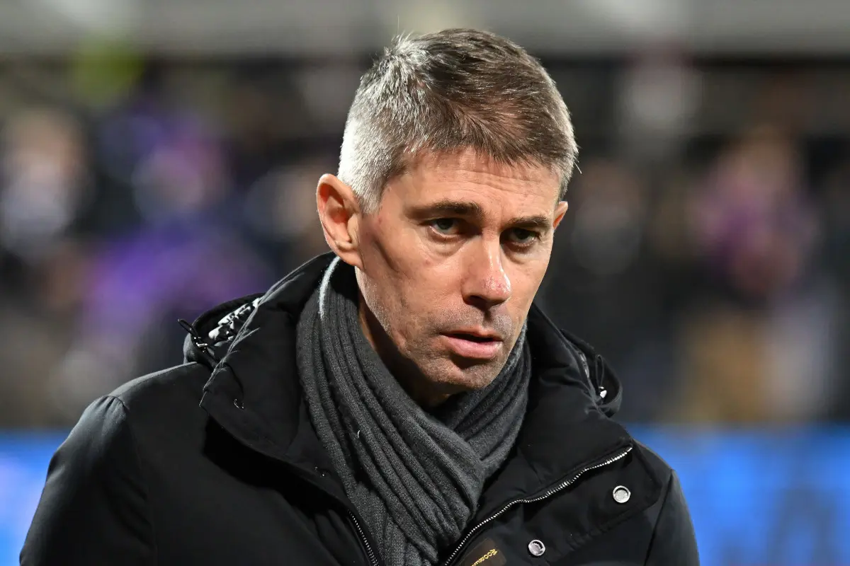 Portrait of Ricky Massara wearing a black jacket and grey scarf at a sporting event.