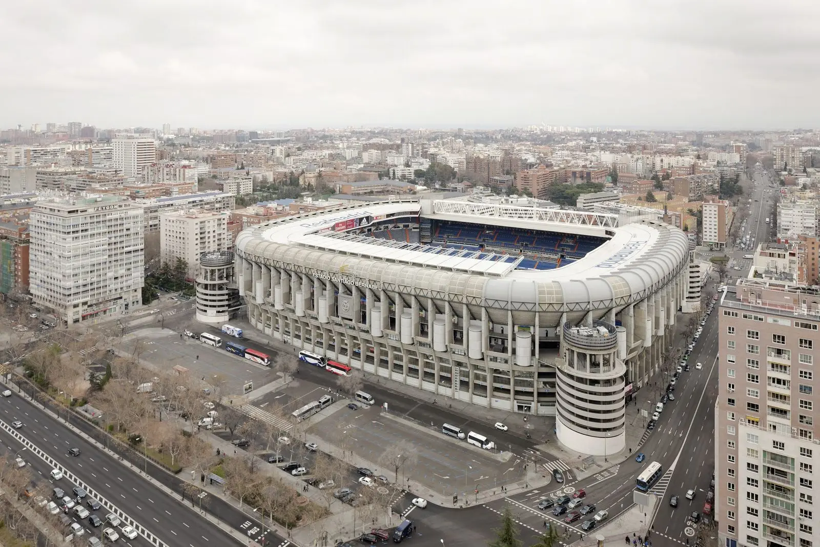 Aerial view of the Santiago Bernabéu Stadium exterior in Madrid, surrounded by city buildings and roads.