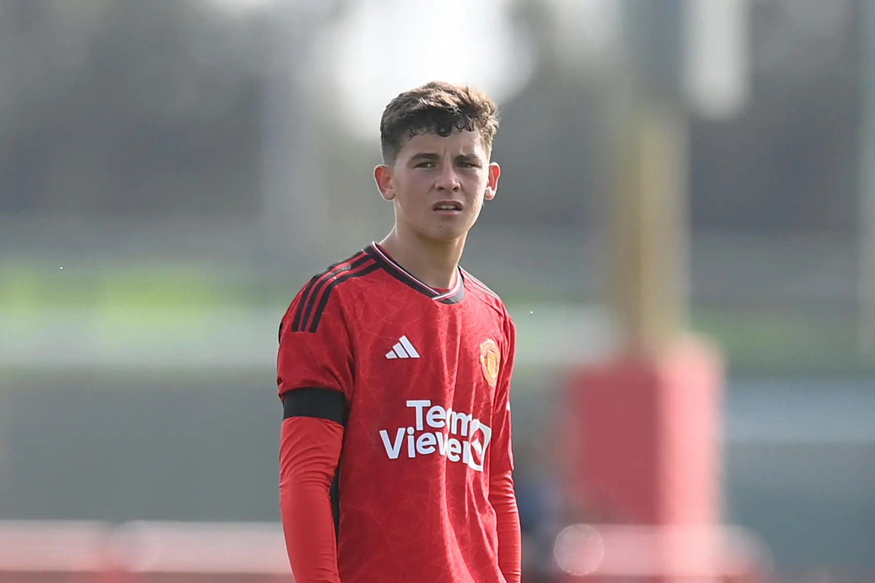 Shea Lacey in a red Manchester United training kit on a football pitch