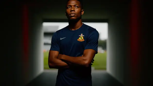 Footballer in Southampton kit stands in stadium tunnel with dramatic red accent lighting