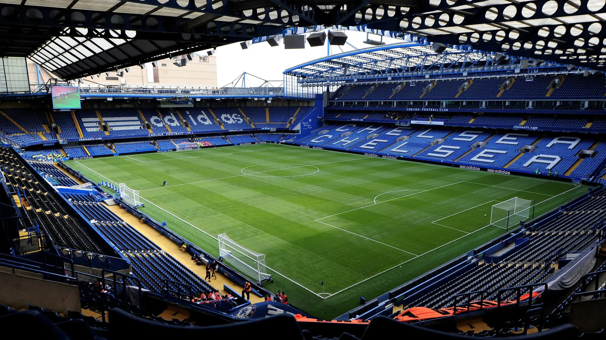 Wide aerial view of the empty pitch and blue seating at Stamford Bridge stadium