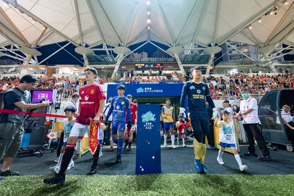 Youth soccer players entering a field at the Antonio Valencia JC Youth Academy event in Hong Kong.