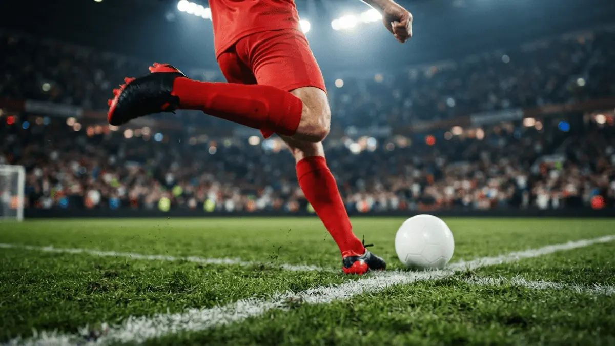 Striker in red socks preparing to shoot inside penalty box with dramatic stadium lighting
