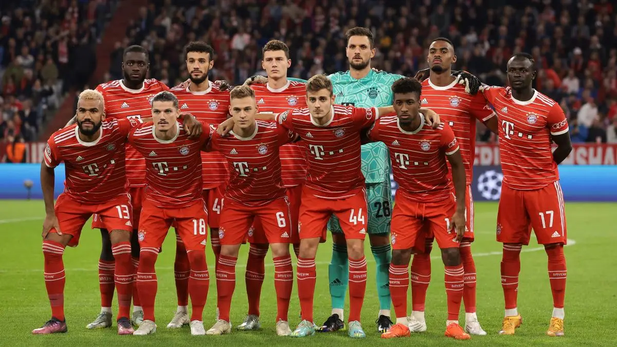 Bayern Munich football squad posing for a team photo in red jerseys on the pitch before a match