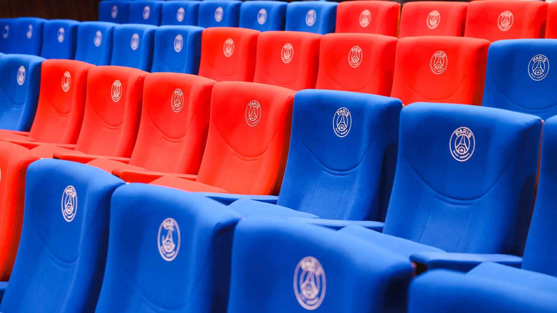Rows of empty red and blue stadium seats featuring the Paris Saint-Germain logo