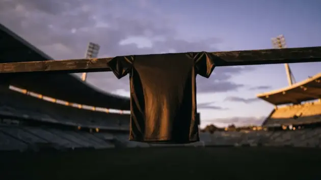 Football jersey hanging on goalpost at sunset in empty stadium symbolizing player career decision