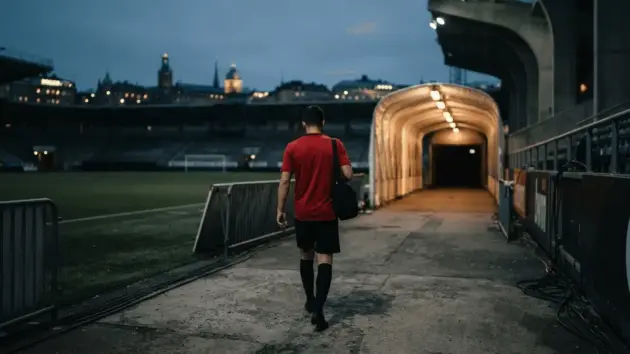 Anonymous Manchester United-style player approaching a floodlit stadium before a preseason debut