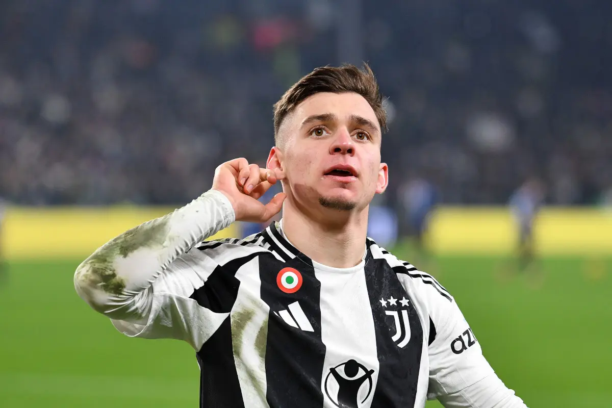 Francisco Conceição wearing a Juventus home jersey, pointing to his ear during a match