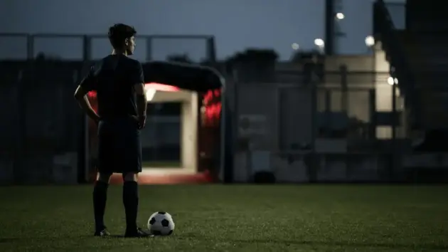 Young striker standing on a football pitch after a transfer approach is rejected