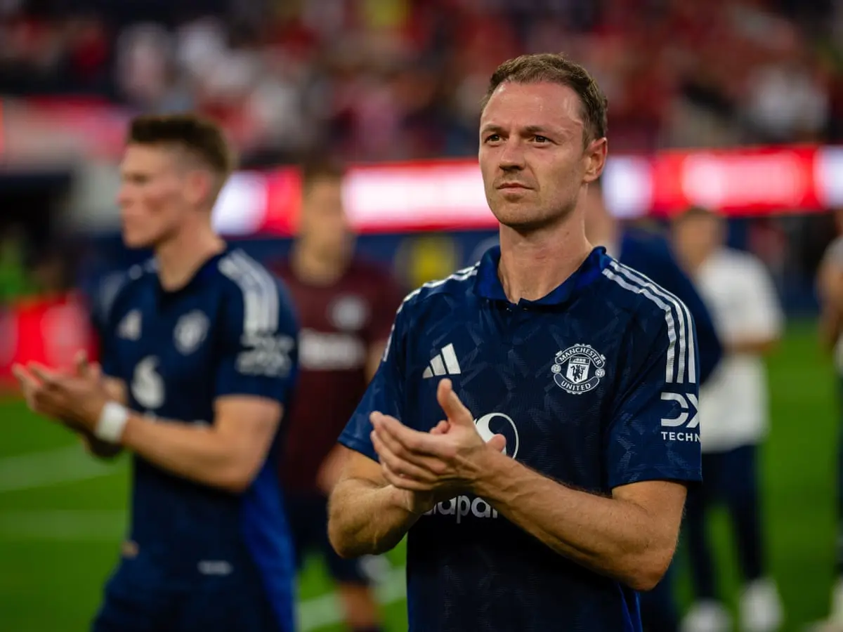 Jonny Evans wearing a navy Manchester United training shirt and clapping on a football pitch