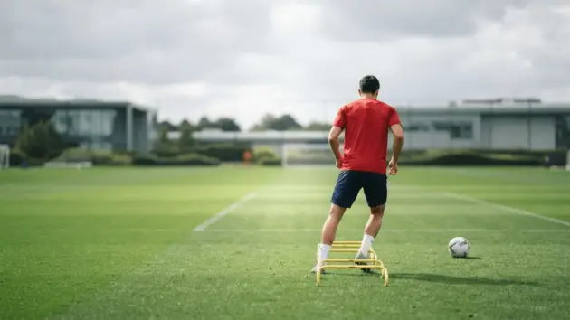 Football defender training alone on a pitch during injury recovery