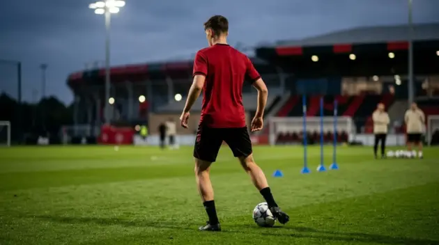 Anonymous young midfielder controlling the ball on a training pitch during a potential Manchester United transfer