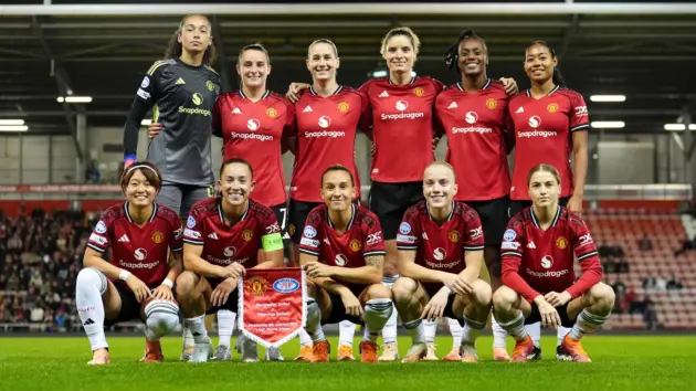 The Manchester United Women's football team posing for a group photo on the pitch.