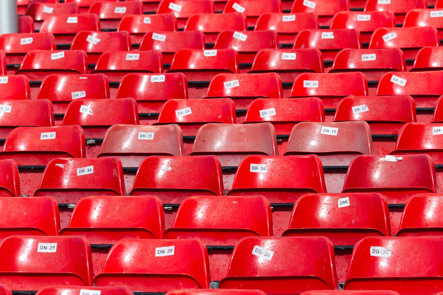 Rows of empty red stadium seats with numbered labels before a Manchester United home fixture